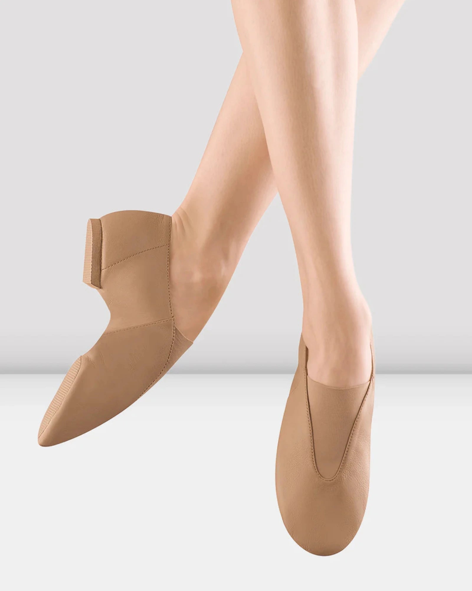 Nude-colored jazz shoes worn by a person on a light gray background