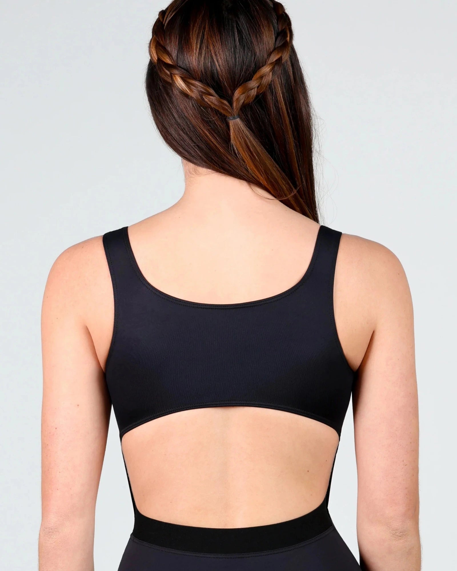 Person wearing a black leotard with cut-out design on a plain background