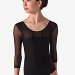 A young female dancer wearing a black three-quarter sleeve leotard with sheer mesh sleeves, shown from the waist up against a light gray studio background.