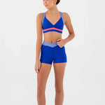 Woman wearing a blue bra top and shorts set on a white background