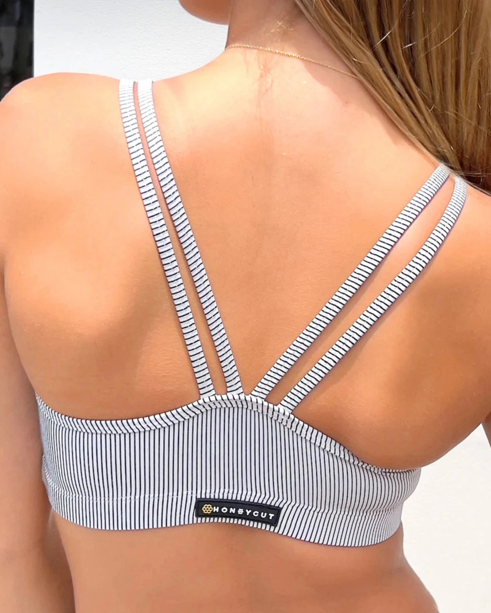 Woman wearing a striped dance top with 'Honeycut' branding.