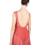 Woman wearing a coral-colored leotard with matching mesh skirt with an open back on a white background