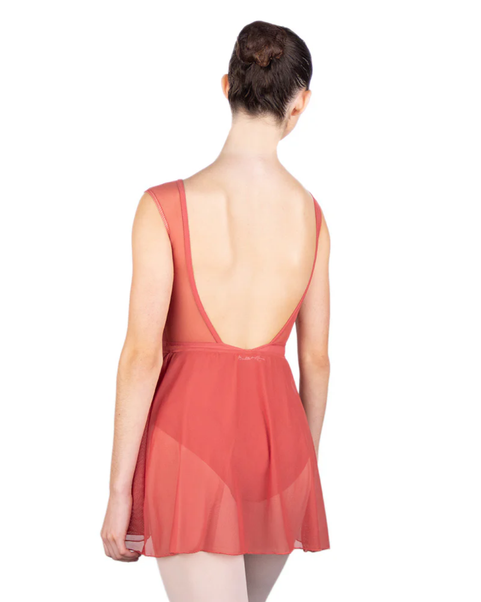 Woman wearing a coral-colored leotard with matching mesh skirt with an open back on a white background