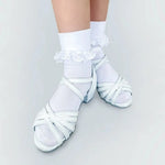 White dance shoes with ruffled ankle socks on a light gray background