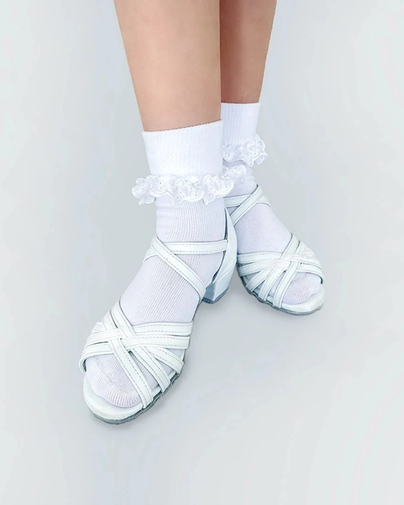 White dance shoes with ruffled ankle socks on a light gray background