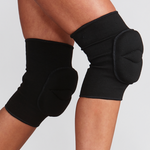 Black knee pads on a person's legs against a light gray background
