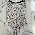 A leotard with a black and white abstract line pattern, laid flat on a white and gray marble surface.