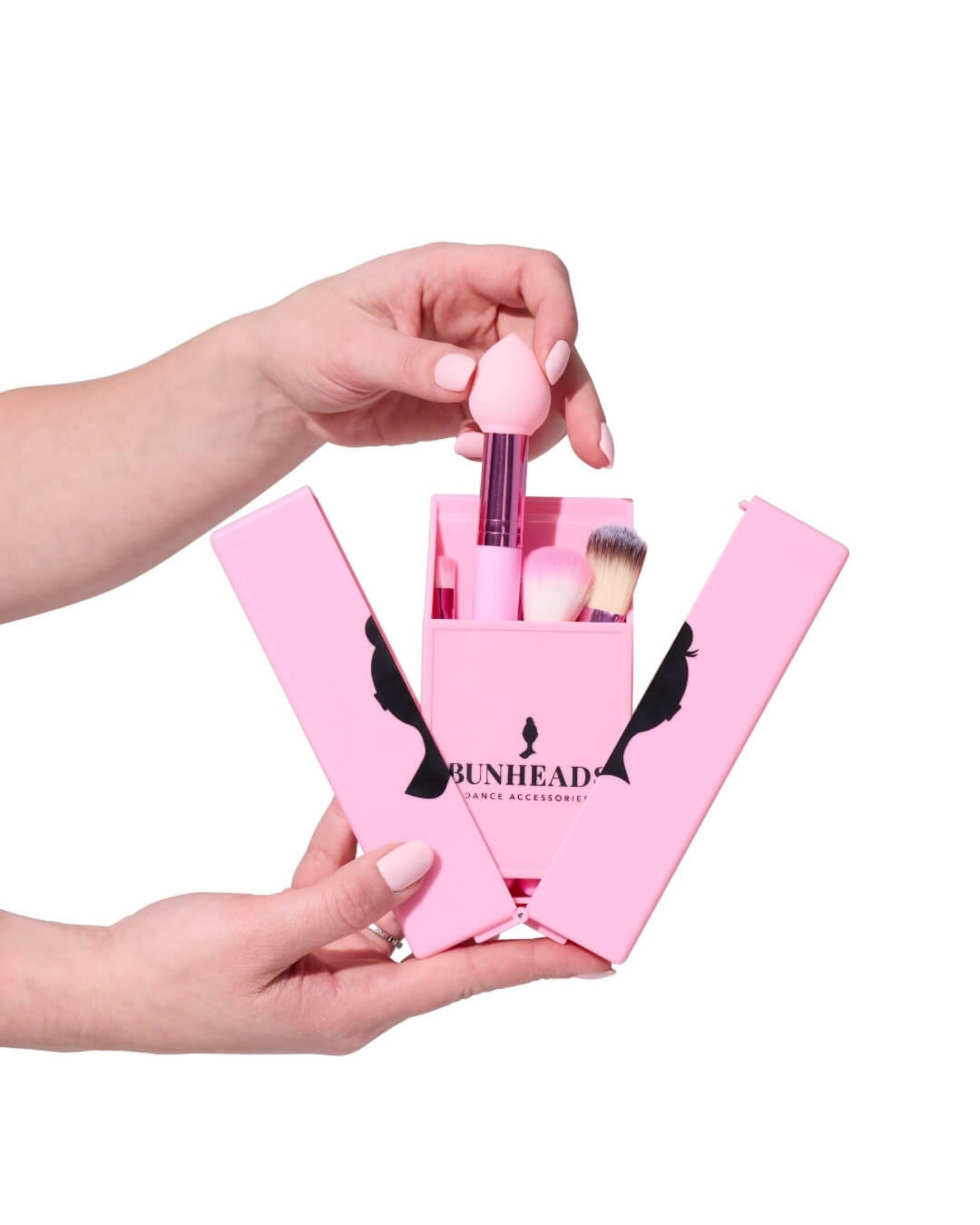 Pink makeup brush set with 'Bunhead' branding held by a hand against a white background