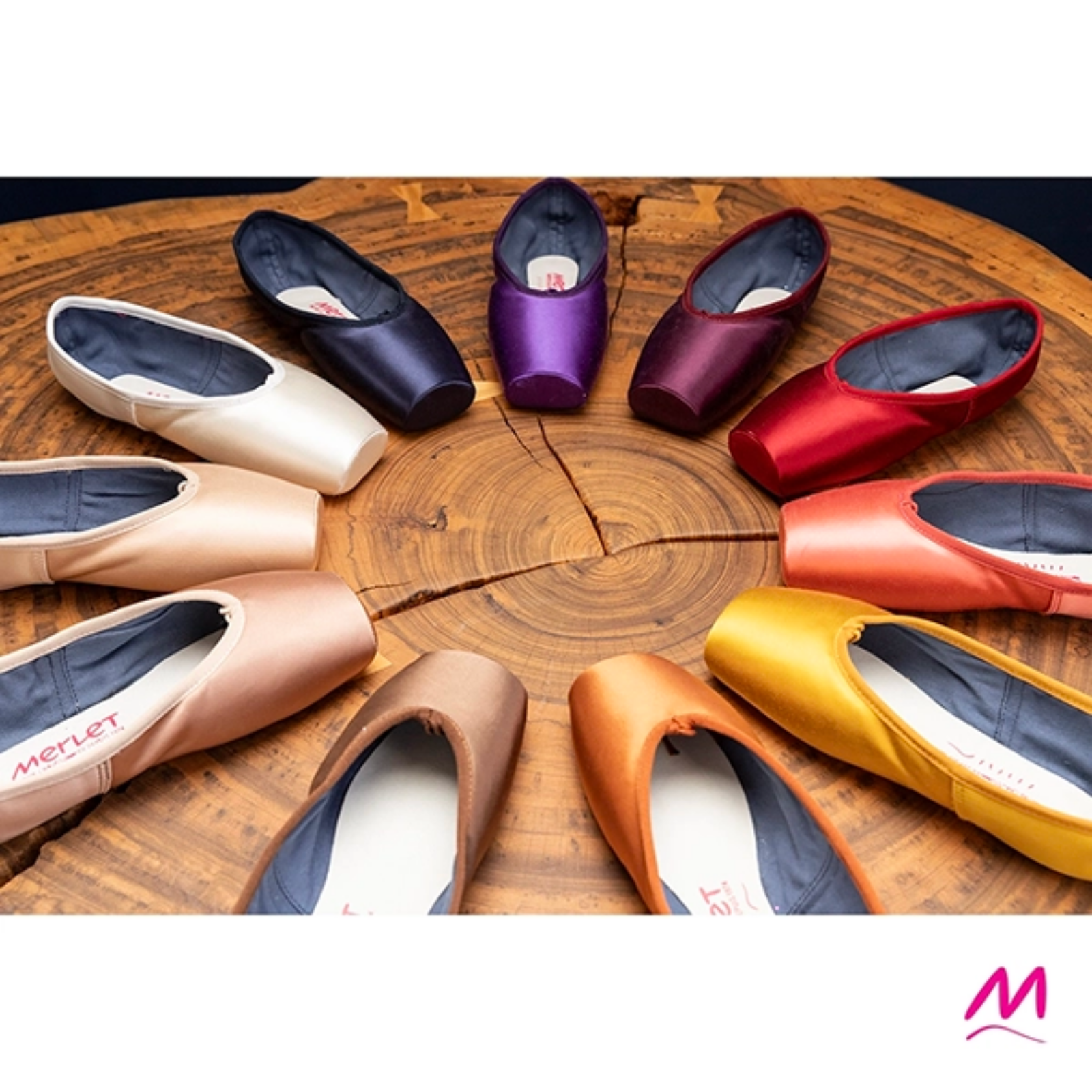 Colorful ballet shoes arranged in a circular pattern on a wooden surface