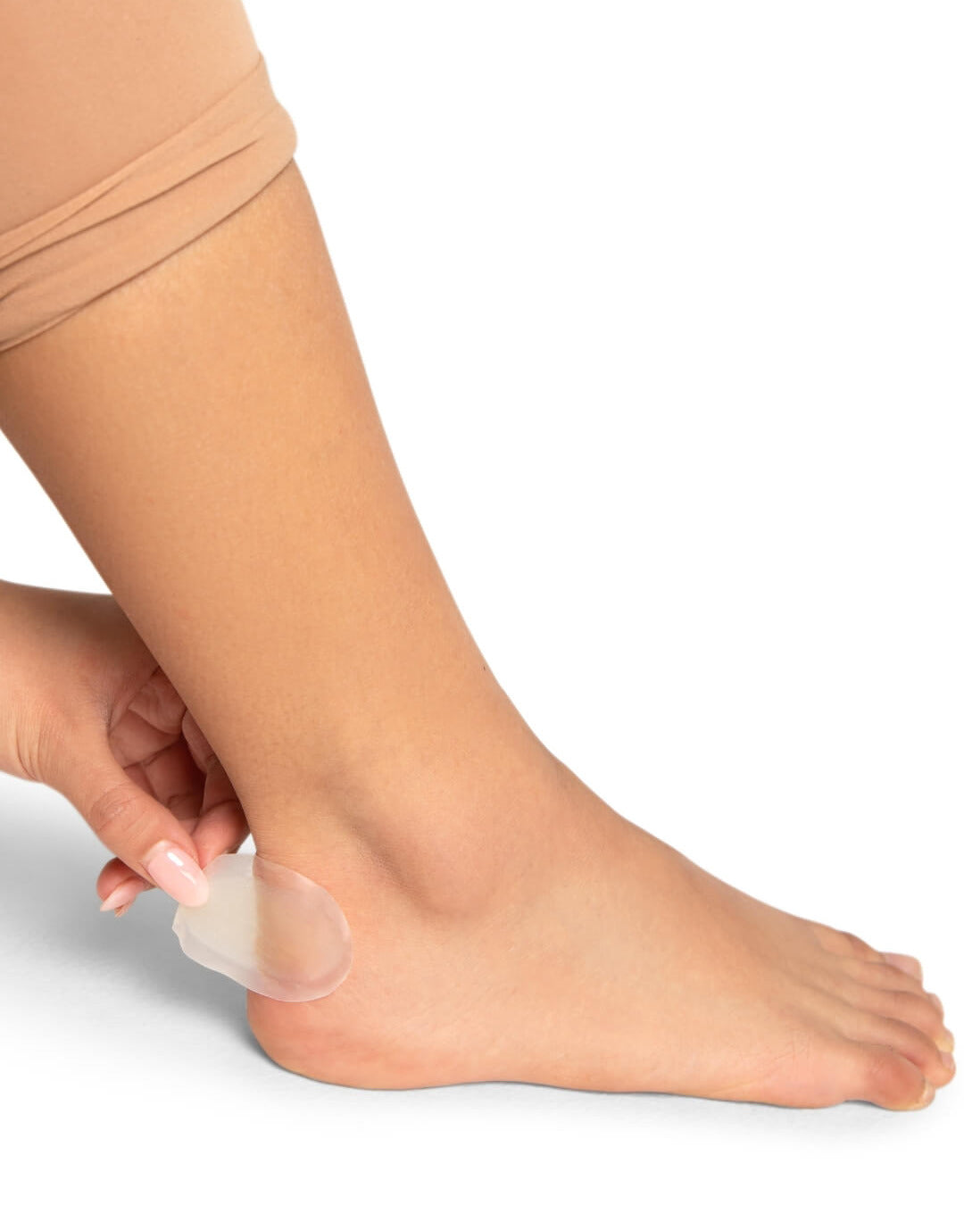 Person applying a clear adhesive patch to their foot on a white background