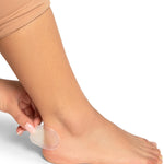 Person applying a clear adhesive patch to their foot on a white background