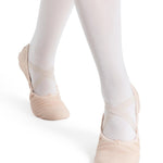 Ballet shoes worn with white tights on a white background