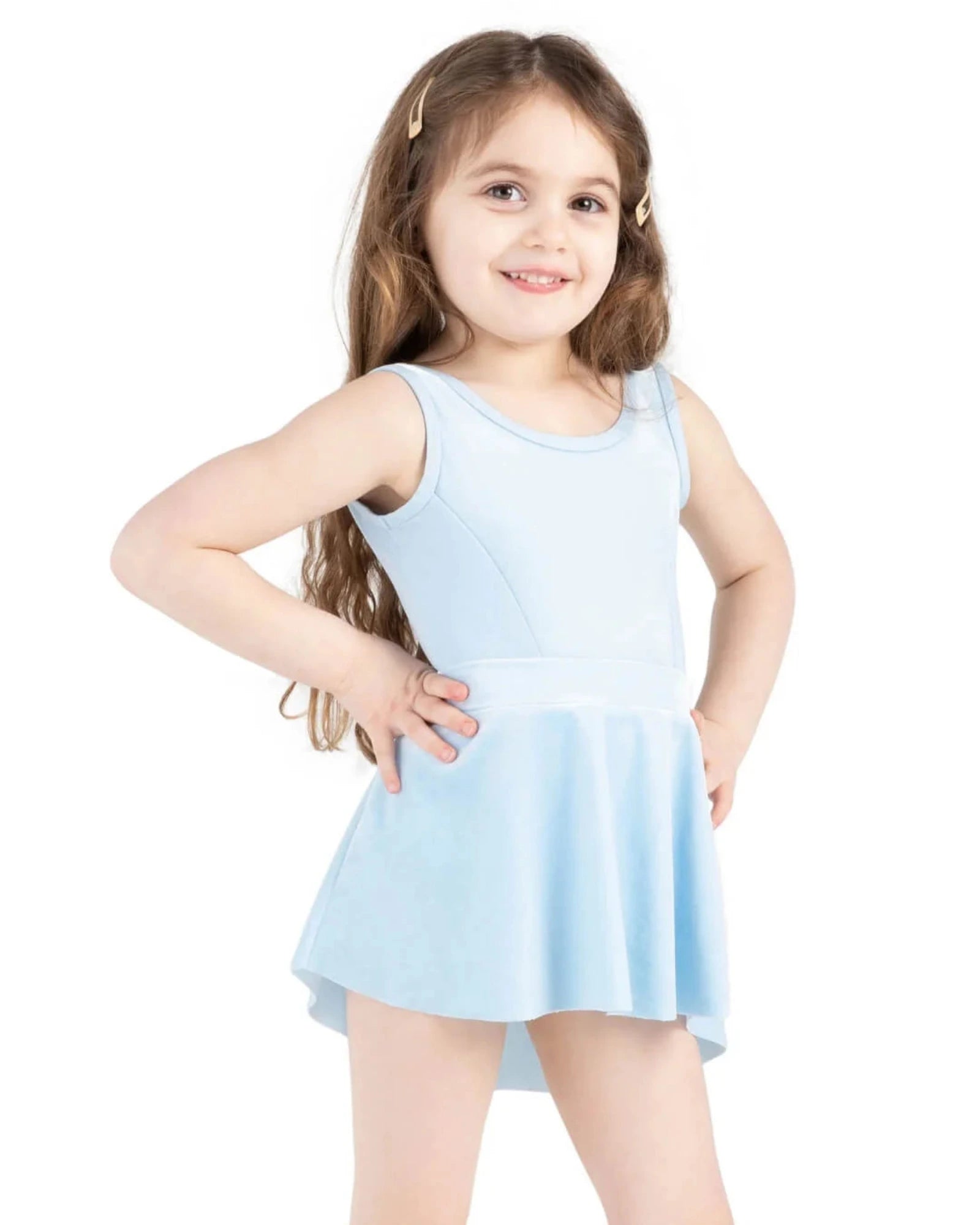 A young girl with long brown hair wearing a light blue sleeveless dance leotard dress, posing with hands on hips against a solid white background.