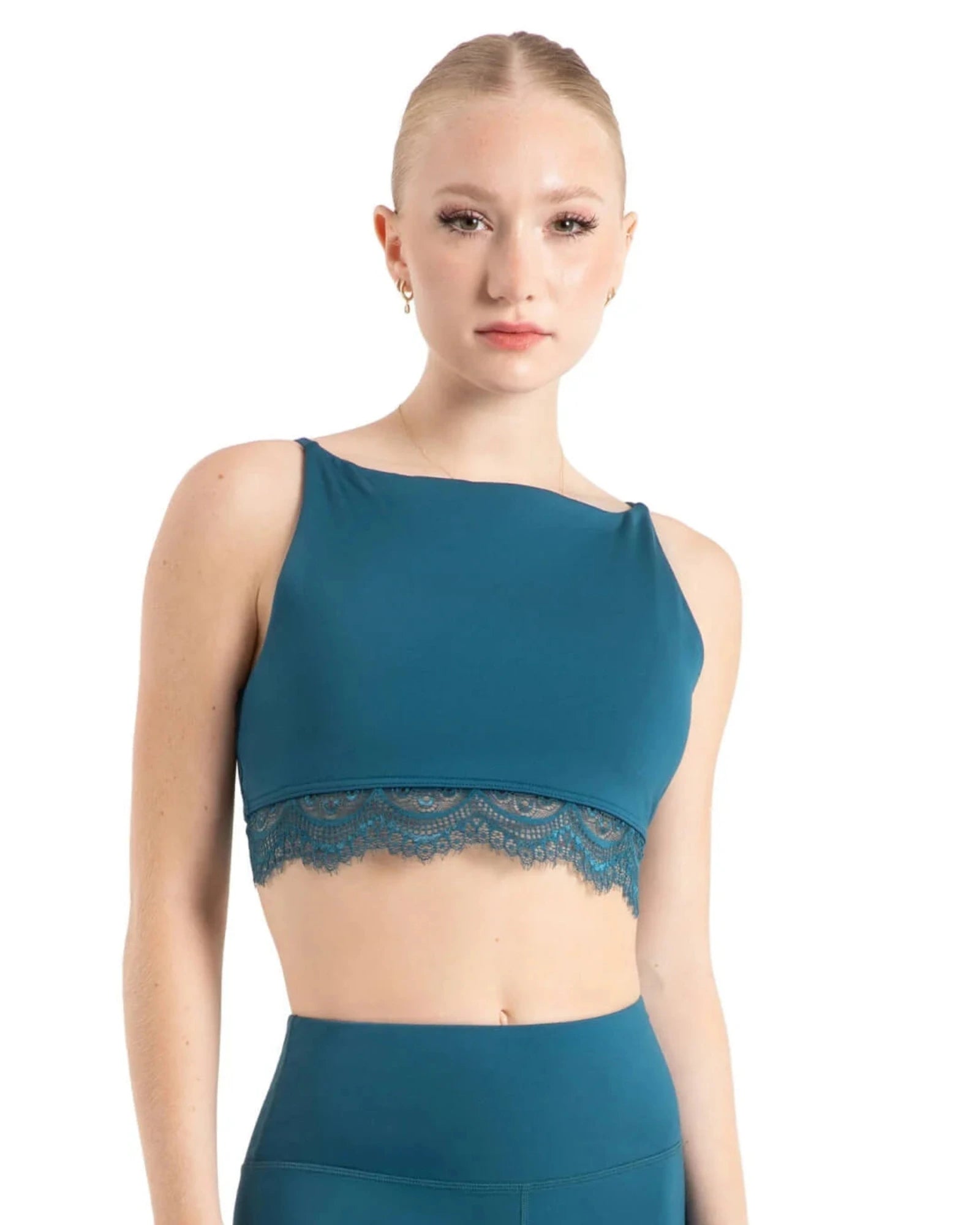 Woman wearing a teal dance bra and leggings on a white background