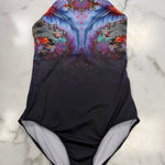 A one-piece halter leotard laid flat on a white marble surface. The leotard features a vibrant, symmetrical fractal floral pattern in shades of purple, blue, pink, and orange on the upper half, fading into a solid black lower half with a light gray interior lining.