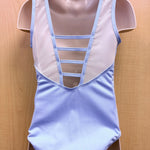 A light blue and white sleeveless leotard displayed on a beige mannequin torso against a light wood background.