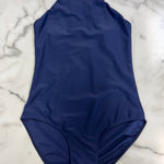 A royal blue sleeveless one-piece leotard with a mock neck, laid flat on a white marble background.