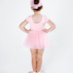 Young girl in a pink ballet outfit with a tutu and headband on a white background