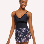 Woman wearing a navy blue leotard and floral skirt on a white background