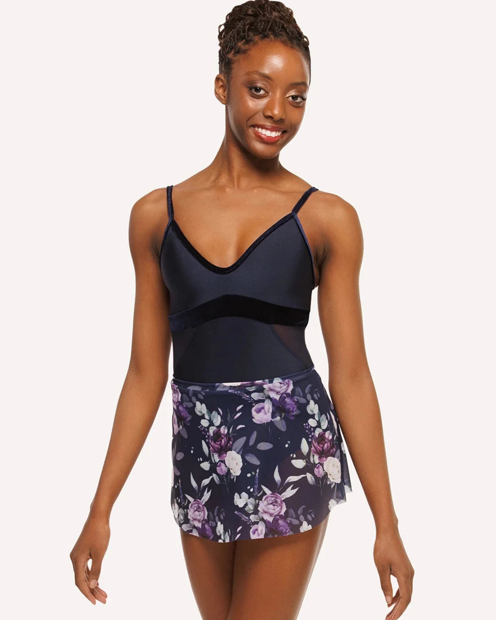 Woman wearing a navy blue leotard and floral skirt on a white background