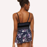 Woman wearing a navy blue leotard and floral skirt on a white background
