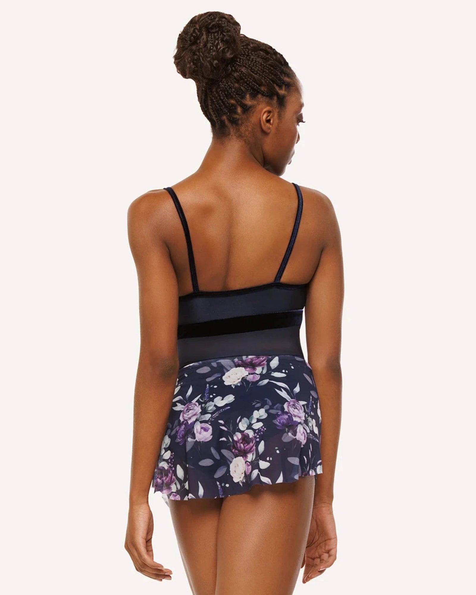 Woman wearing a navy blue leotard and floral skirt on a white background