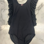 A black one-piece leotard with ruffled shoulder details and a small pink bow accent at the neckline, laid flat on a white marble surface.