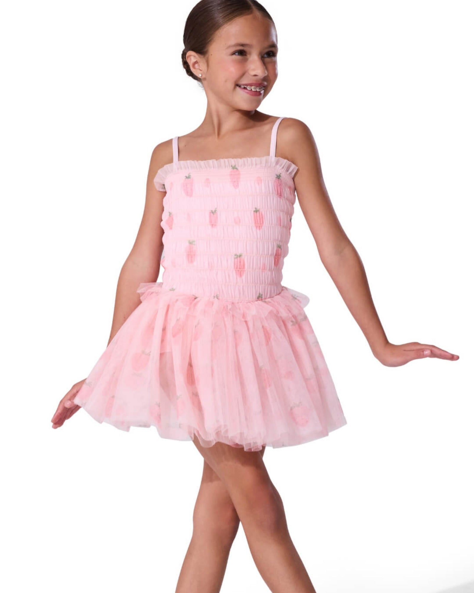 Young girl wearing a pink ballet dress with strawberries on a white background