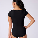 Woman wearing a black leotard against a white background