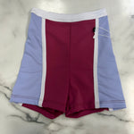 Colorblock dance shorts in light purple, burgundy, and white, laid flat on a white marble surface.