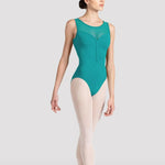 A female dancer in a sleeveless teal leotard, pink tights, and pointe shoes, standing en pointe against a light gray studio background.