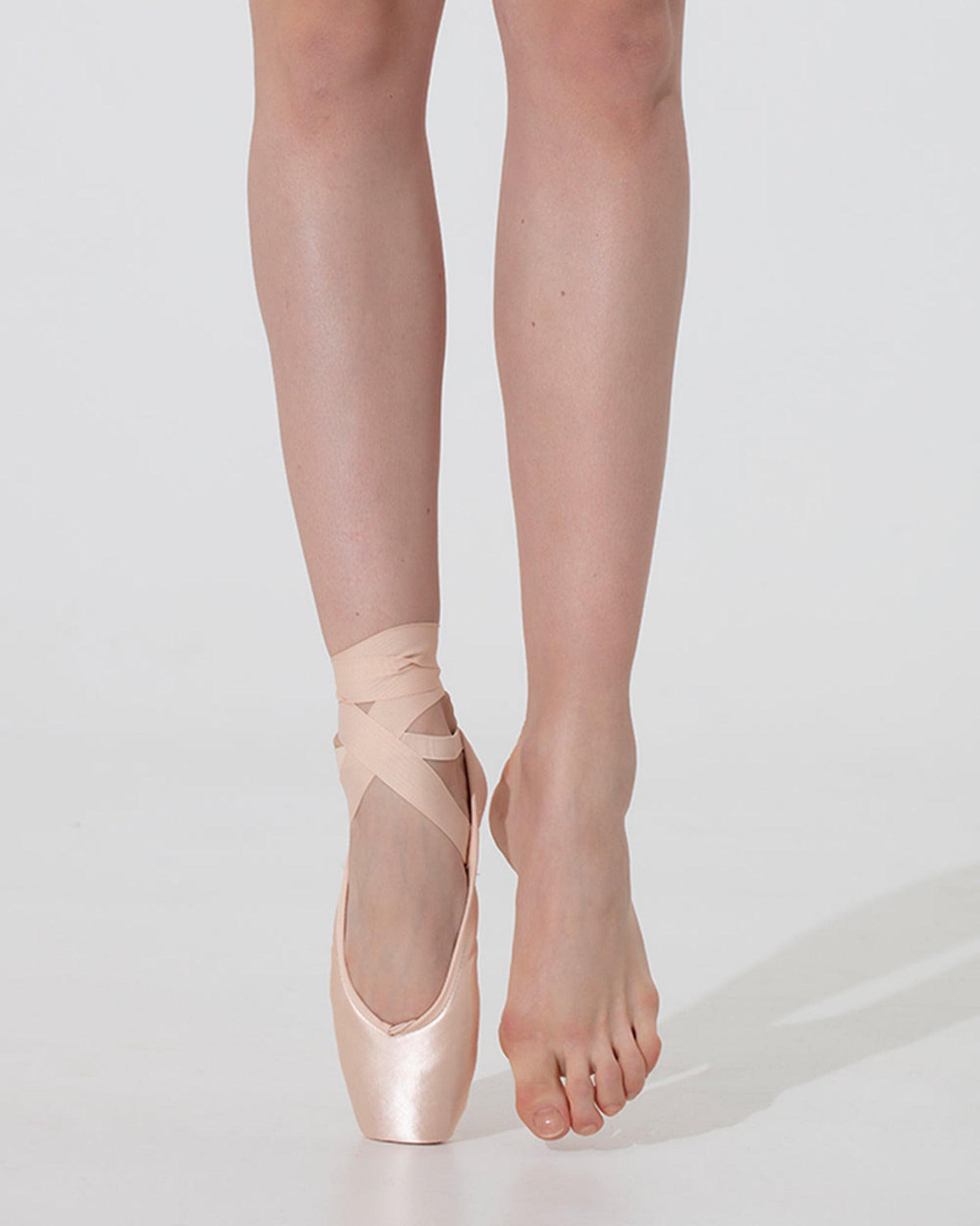 Ballet dancer wearing pink ballet shoes on a white background