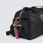Black duffel bag with gold zipper and pink tag on a light gray background