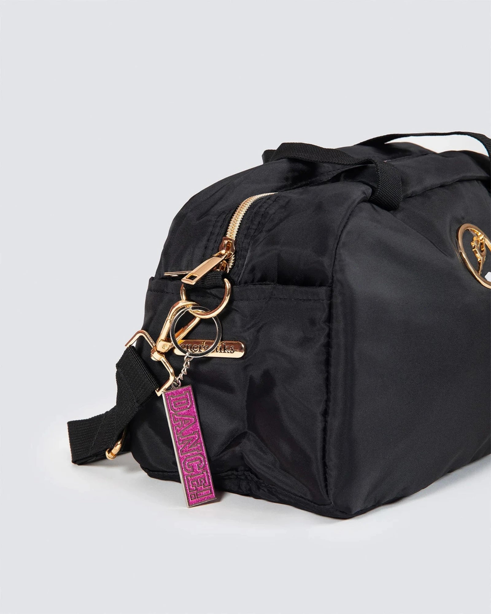 Black duffel bag with gold zipper and pink tag on a light gray background