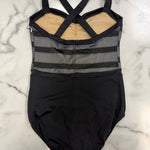 A black leotard with a sheer gray striped bodice, crossed shoulder straps, and a beige lining, laid flat on a white marble surface.