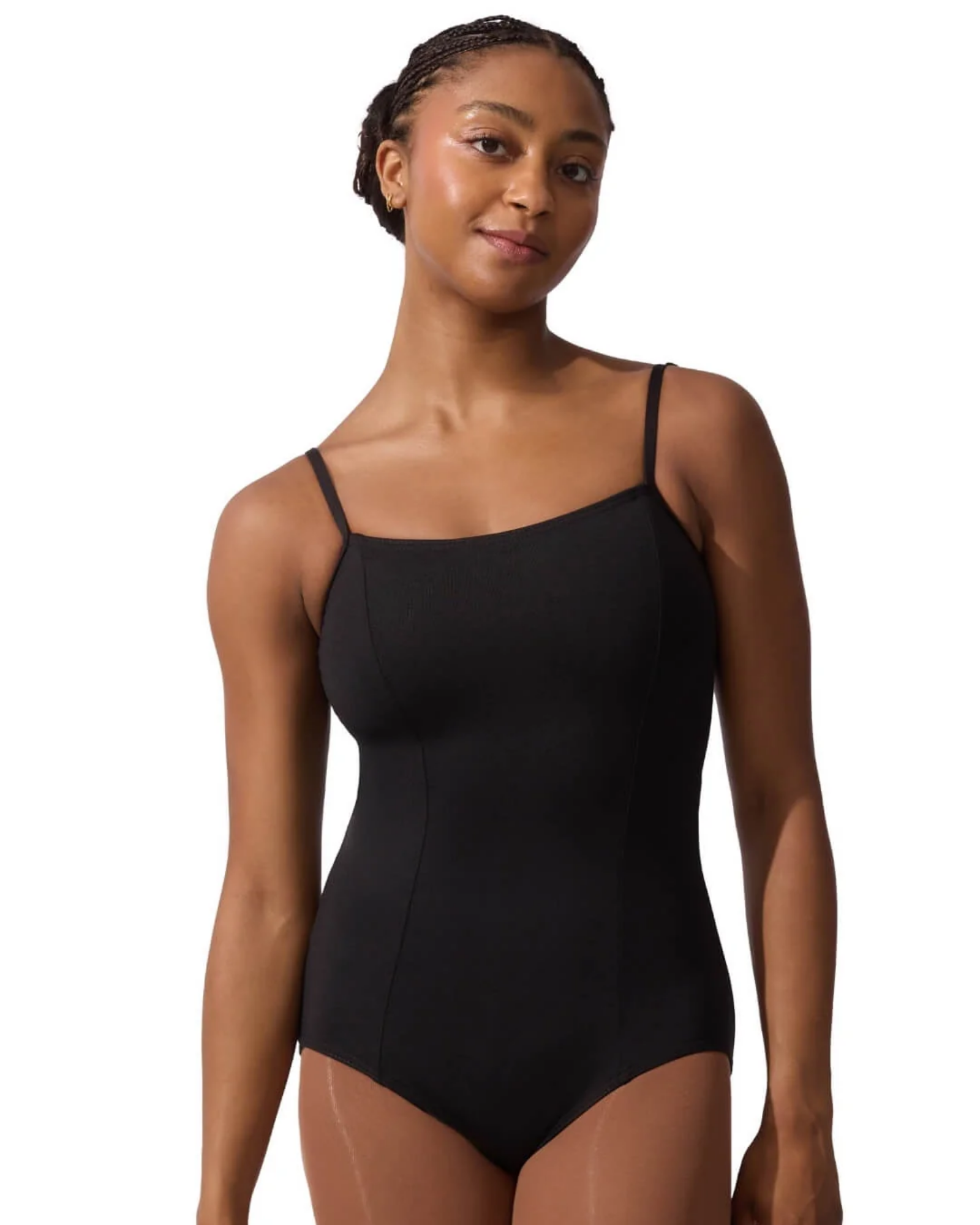 A woman modeling a black camisole-style leotard with thin shoulder straps against a plain white studio background.