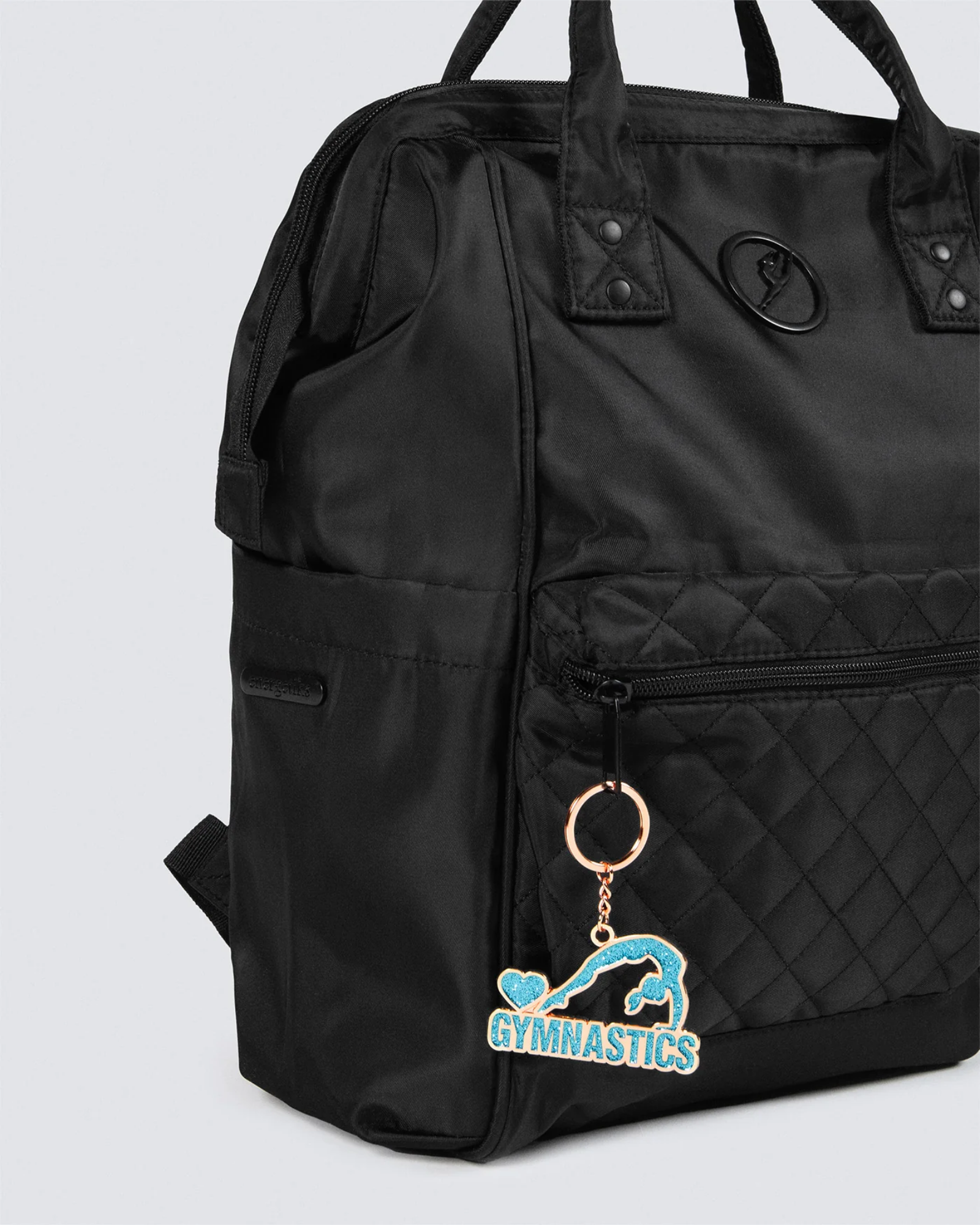 Black backpack with a keychain featuring a gymnastics design on a light gray background