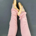 Pointe shoes with pink legwarmers against a dark background