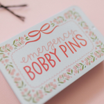 Tin box with 'Emergency Bobby Pins' text on a pink background