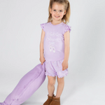Young girl in a purple top with matching pants on a white background