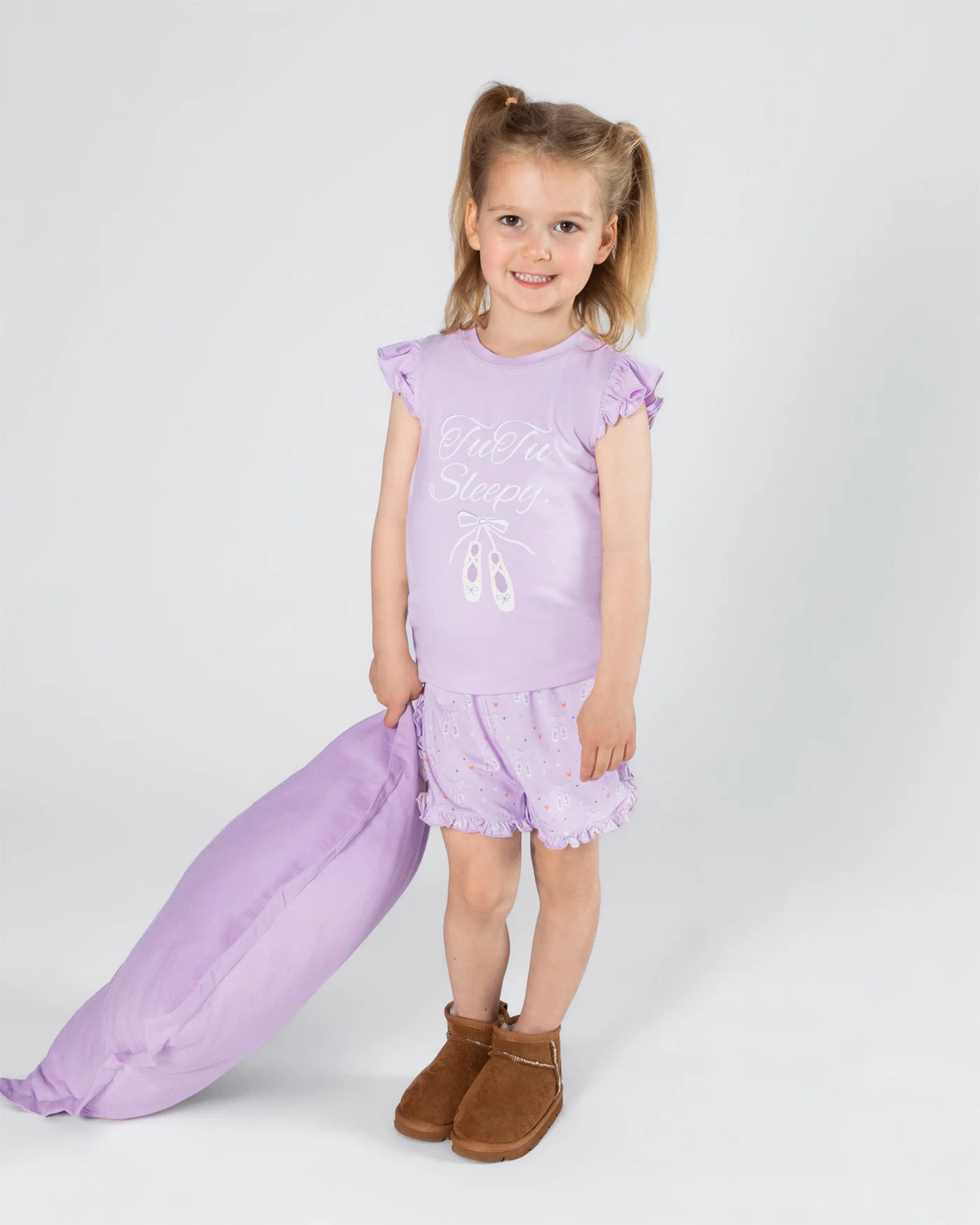 Young girl in a purple top with matching pants on a white background