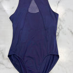 A sleeveless dark purple leotard laid flat on a white marble surface, featuring a high mock neck with a keyhole cutout at the back.