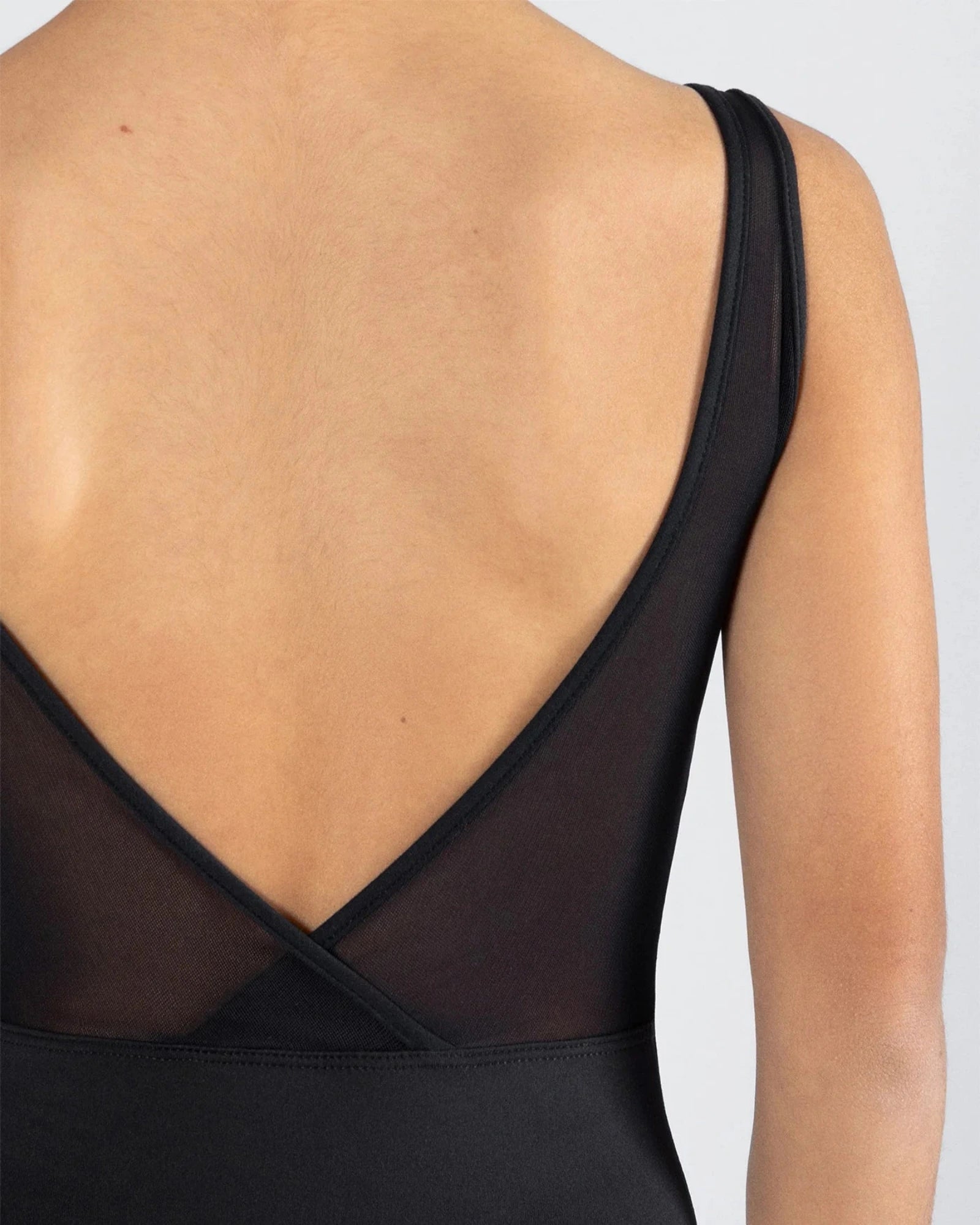 Black leotard with sheer back detail on a plain background