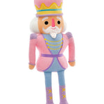 A plush nutcracker doll with a pink and lavender outfit, yellow accents, and a white beard, standing against a plain white background.