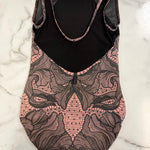 A sleeveless leotard laid flat on a white marble surface, featuring a mesh black upper back and black lining with a pink and black lace-like patterned lower body.
