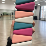 Stack of colorful leg weights held in a hand with a dance studio background