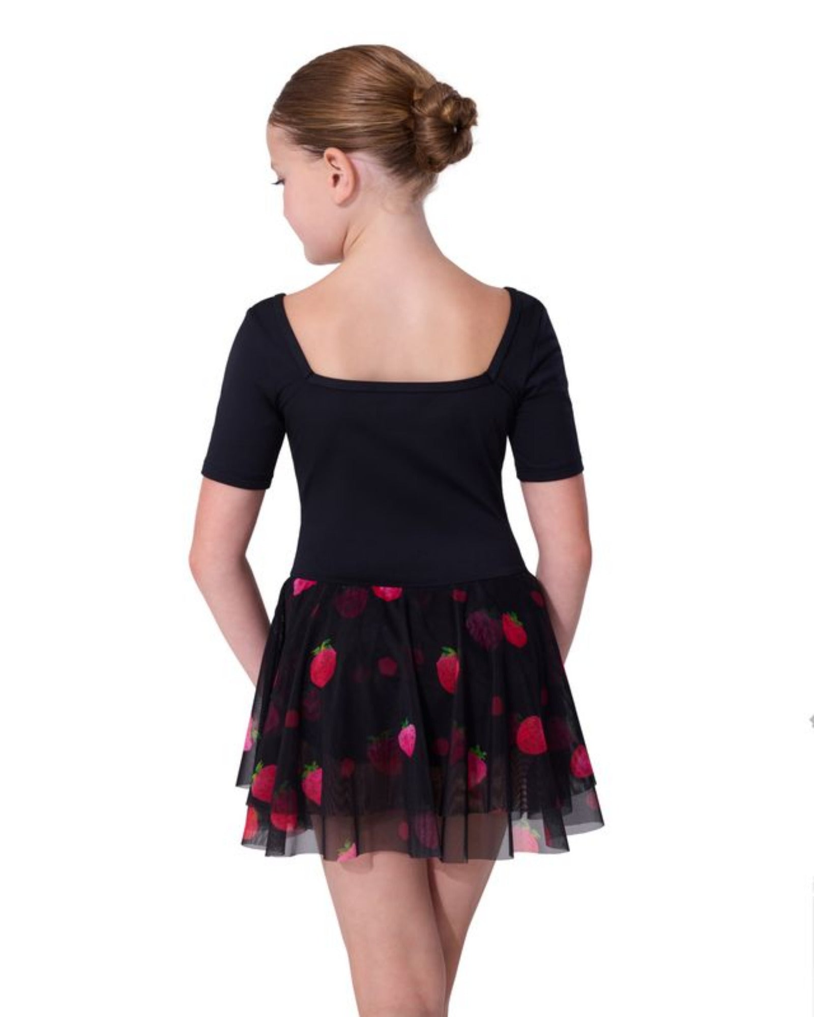 A young girl is shown from the back wearing a black short-sleeve dress with a square neckline and a tulle skirt featuring a red strawberry pattern