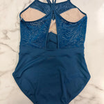 A blue leotard with a zebra textured pattern on the upper section, beige lining, and a back keyhole detail, laid flat on a white marble surface.