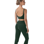 A woman shown from the back wearing a dark green sports bra and matching high-waisted leggings against a plain white background.