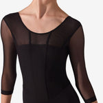 A female dancer wearing a black leotard with sheer three-quarter sleeves and a scoop neckline, shown against a plain light gray studio background.